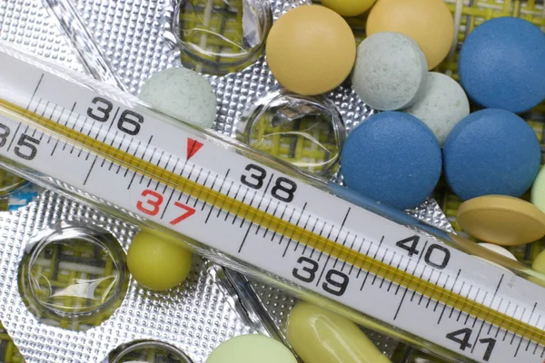 Tablet, kapsül ve tıbbi termometre, soğuk algınlığı ve grip tedavisi kavramı.