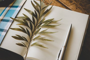 Güzel kurumuş yapraklar bir defter ve tahta bir masa üzerinde kalem.