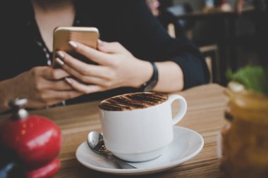 Bir kafede akıllı telefondan mesaj yazan bir kadın. Genç bir kadının kahve masasında cep telefonu kullanırken çekilmiş görüntüsü.