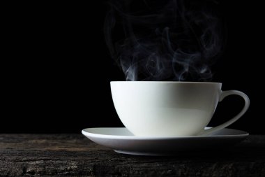 Koyu renkli, beyaz bir fincan kahve. Tahta masa. Sıcak içecek..