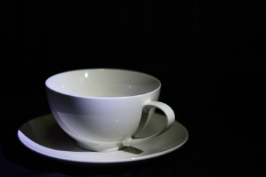 Koyu renkli, beyaz bir fincan kahve. Tahta masa. Sıcak içecek..