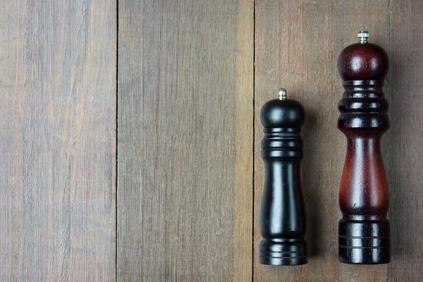 Pepper mill placed on the wooden floor, top view.