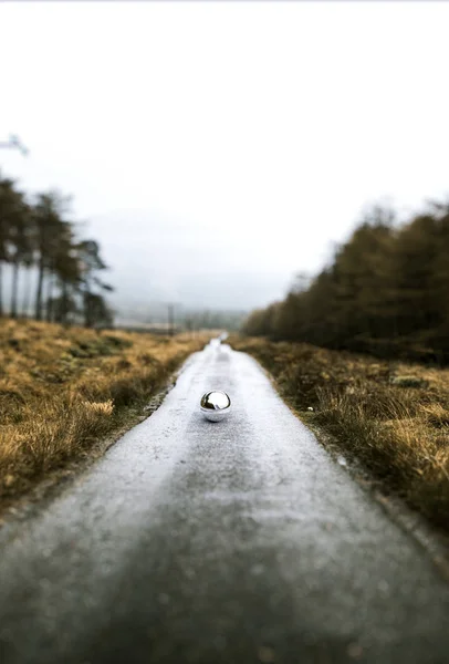 Esfera metálica na estrada vazia — Fotografia de Stock