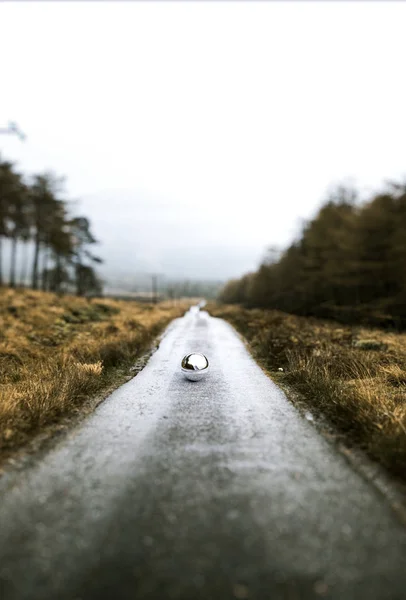 Metallic sphere on empty road — Stock Photo, Image