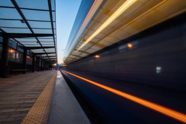 Hareket bulanık tramvayı olan boş bir tramvay platformu. Gün batımında hafif raylı sistem platformu.