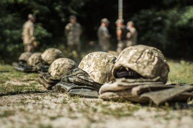 Askeri miğferler ve kurşun geçirmez yelekler çimlerin üzerinde dizilmiş..