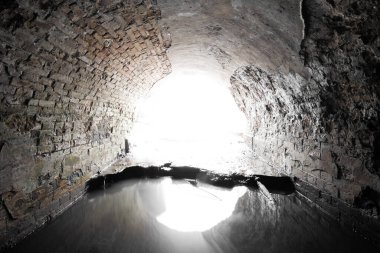 Eski tuğla terk edilmiş yarı dairesel drenaj tüneli dışarı çıkıyor..