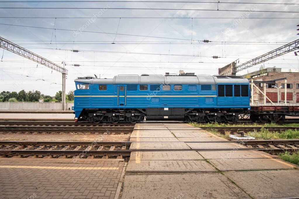 Blue shunting locomotive rides at the train station.