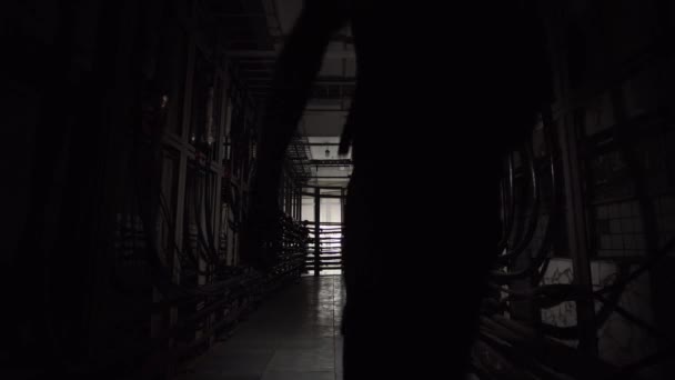 多くのケーブルのある地下トンネルを提灯を持った男が歩いている — ストック動画