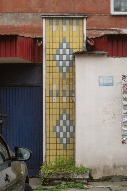 Geometrik kaplı sarı kiremit duvar deseni 1970 'lerde inşa edilmiş 96 serisinden oluşan bir panelin girişinde. Voskresenka, Kyiv, Ukrayna, 31 Temmuz 2025.