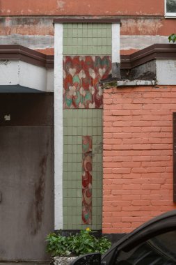 Seramik seramik kaplama duvar grafiği ve çiçek süsü, Voskresenka Mahallesi 'nde yer alan 96. serinin girişi. Voskresenka, Kyiv, Ukrayna, 31 Temmuz 2025.