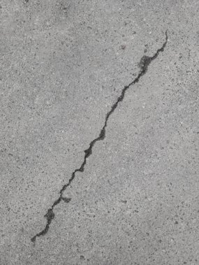 Gri asfalt yol yüzeyinde çapraz çatlak.