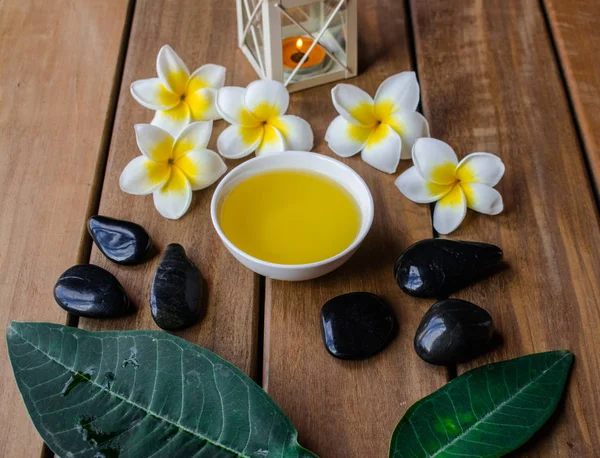 Massageolja Med Plumeria Blommor Och Svarta Runda Stenar Träytan — Stockfoto