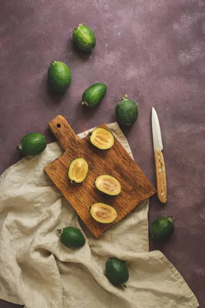 Feijoa fruit cut in halves on a cutting board. Top view, flat lay