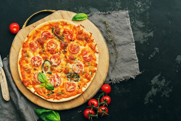 Pizza Margarita with cherry tomatoes, mozzarella and Basil on a cutting Board. Top view, flat lay. Toned photo.