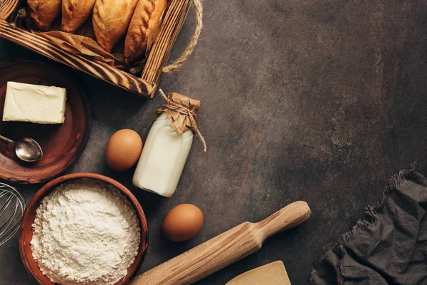 Baking background, ingredients for cooking pies, flour, butter, milk, eggs. Traditional Russians baked patties, pirozhki. Overhead,copy space.