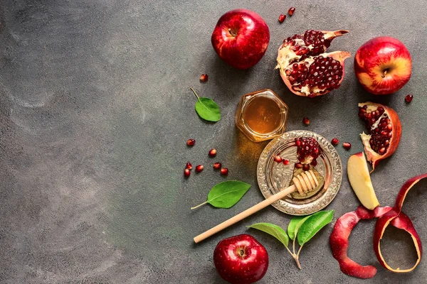 Jewish New Year - Rosh Hashanah. Apples, pomegranate and honey on a dark rustic background. Traditional Jewish food. Top view, flat lay,space for your text.