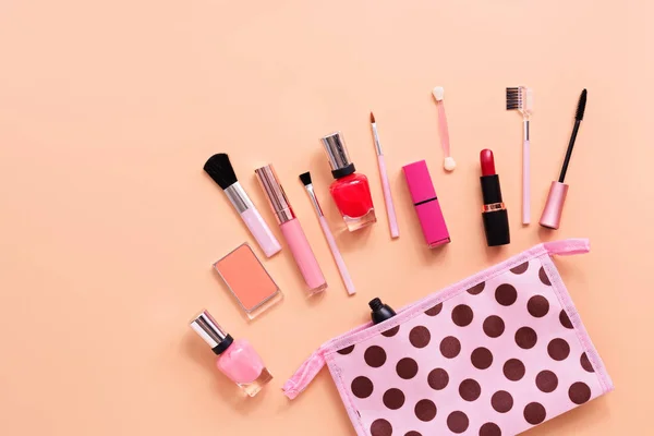 Various women's makeup cosmetics on a soft pink background. Cosmetic bag, blusher, mascara, lipstick, nail polish and brushes. Top view, flat lay, copy space.