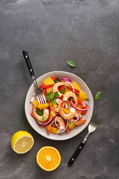 Latin American food. Ceviche salad with shrimps and oranges on a dark rustic background. Top view, flat lay, copy space.