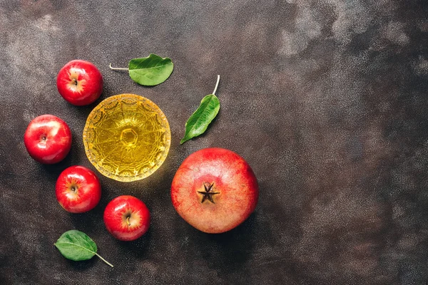 Jewish New Year - Rosh Hashanah. Apples, pomegranate and honey on a dark rustic background. Traditional Jewish food. Top view, flat lay.