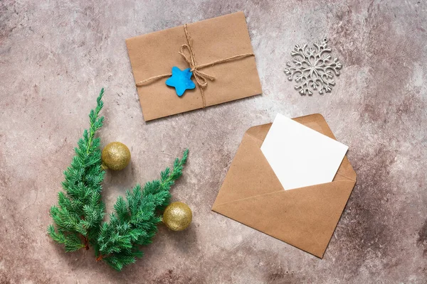 Christmas composition. Blank greeting card mockup in an envelope, juniper branches with golden balls, a letter to Santa Claus. Top view, flat lay