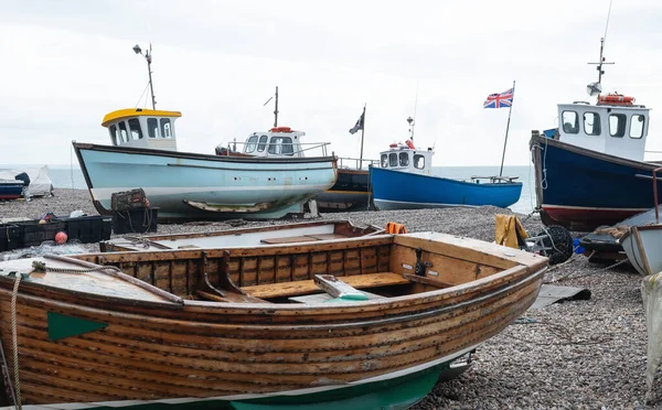 Some of the local fishing fleet stranded on the pebble beach at Beer in south east Devon, UK. Vessels are towed to and from the sea by tractor