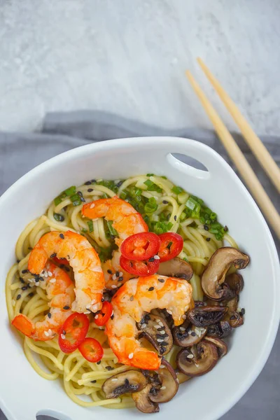 Hot asian wok noodles with shrimps and mushrooms, Ramen, Gray background, Top view