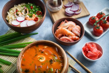Asya gıda, Tom Yam ve Ramen karides, ahşap kase, yumurta noodle, hazırlık, biber biber, soğan ve mantar, baharatlı, ïsïgï Tayland yemekleri ile gri arka plan, portre