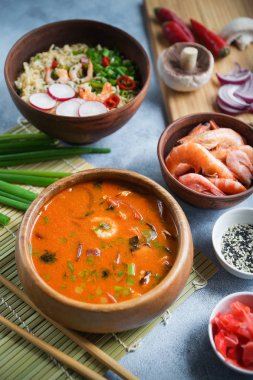 Asya gıda, Tom Yam ve Ramen karides, ahşap kase, yumurta noodle, hazırlık, biber biber, soğan ve mantar, baharatlı, ïsïgï Tayland yemekleri ile gri arka plan, portre