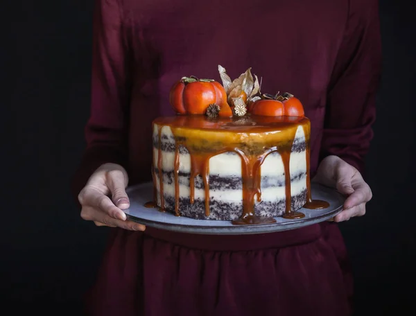 秋天蛋糕与子和焦糖与南瓜和女孩在一个勃艮第礼服在黑色背景 大气黑暗的食物相片 糕点自制 — 图库照片