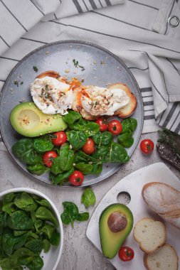 Tost avokado ve haşlanmış yumurta, domates ve ıspanak, bir ışık gri arka plan üzerinde taze sabah