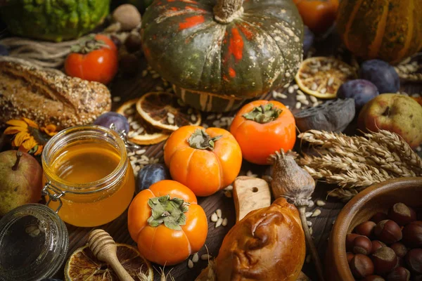 Pompoenen, kaki, granen, brood, zaden en noten op een houten ondergrond, oogst, herfst — Stockfoto