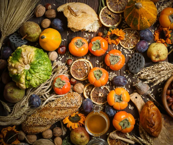 Pompoenen, kaki, granen, brood, zaden en noten op een houten ondergrond, oogst, herfst — Stockfoto