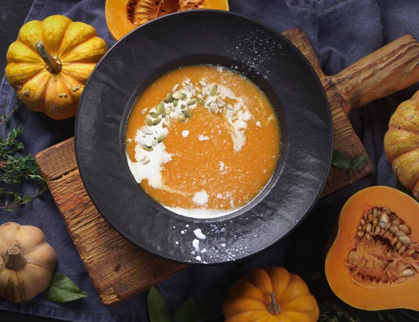 Pumpkin soup in a black plate on a dark background — Stock Photo, Image