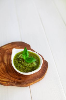 Beyaz bir arka plan üzerinde ahşap bir tahta üzerinde bir sos teknede Pesto sosu