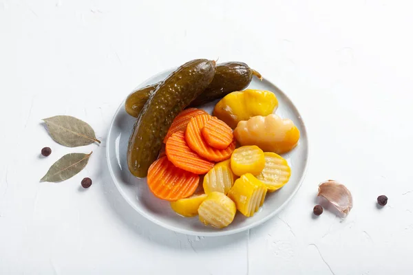 Mayalanmış salatalık, havuç ve kabak karışımı beyaz bir masada.