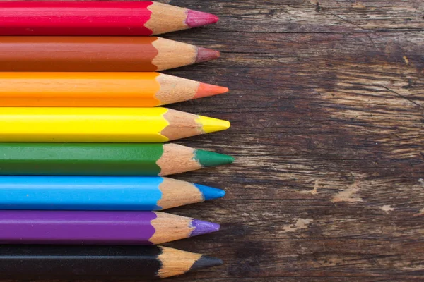 Sharpened colored pencils on a wooden background. Color pencils on a wooden table. Sharp slips of colored pencils close-up. Pencils in the colors of the rainbow. Bright background. Cheerful colors. Multicolored slates. Colors of life.