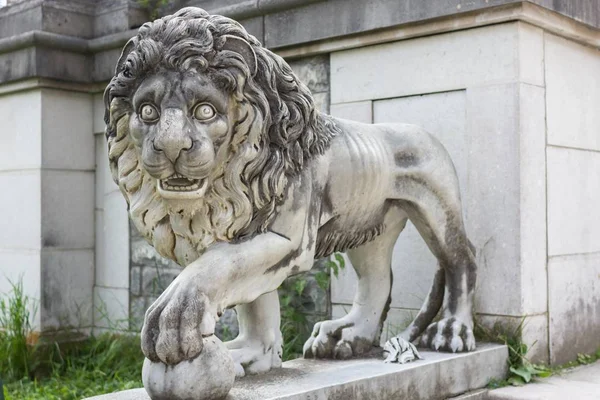 White marble lion by the castle. Marble sculpture. White stone lion. Architecture of the Middle Ages. European monuments. An ancient attraction. Peles Castle in Europe. Sculpture of an animal.