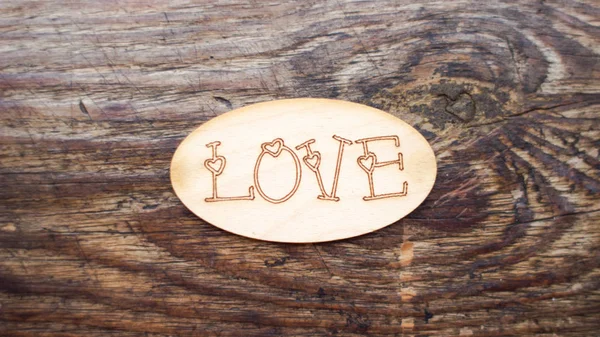 Valentine on a wooden background. Romantic greeting card with the word love on a wooden background. The symbol of unrequited love. Inscription love. Decorative tablet with the word love. Romantic background. Valentine\'s Day. Words of love.