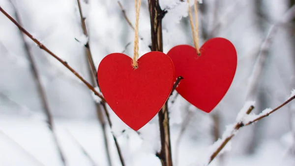 Heart on a snowy background close-up. Red heart against the background of a winter forest. Romantic background with a red heart. Red heart against a background of snow-covered trees. Christmas good. Snow-covered winter park. Comfort in winter.