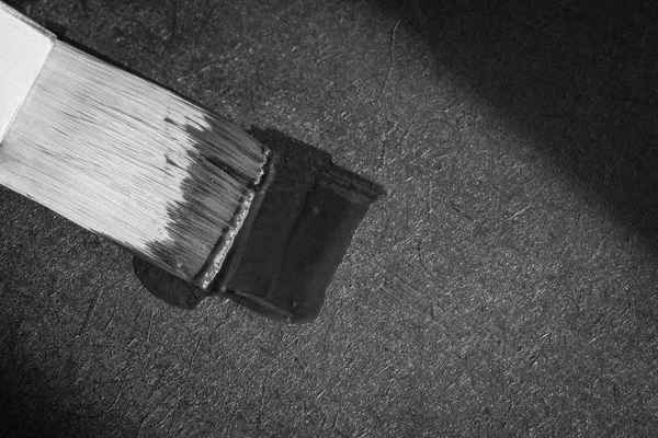 Black paint on a brush on a textured background. Solar flare on black paint. Black band of life. Bank with black slate paint. Making your own interior. Decorating the surface with slate paint. Coloring with black paint.