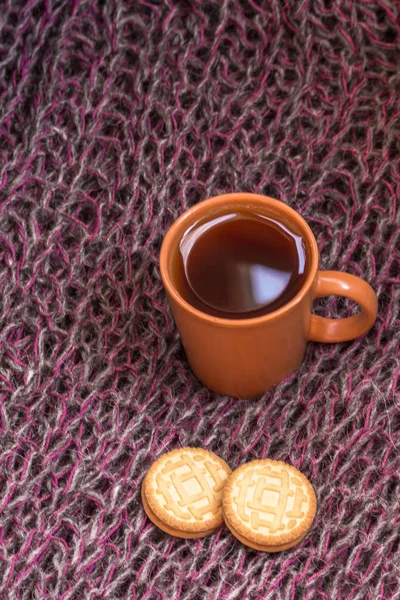 A cup of coffee or tea. Warming drink in winter. Cozy home leisure. Morning espresso with cookies. Knitted background. Relaxing holiday with a cup of cocoa. Comfortable pastime.