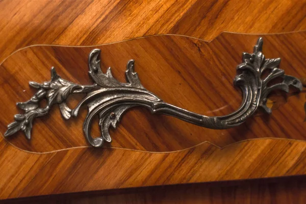 Carved accessories. Bronze or iron handle on the furniture. Exquisite baroque furniture. Vintage chest for clothes. Antique furniture in the interior of the house or hotel. Stylish design.