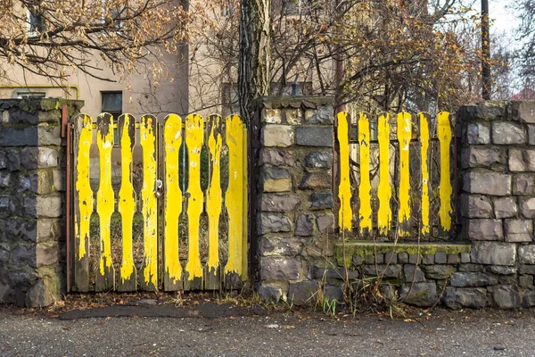 Old stone fence. Yellow wooden gate. Old country architecture. Abandoned house. Old house with a yellow fence and a gate. Private European home.