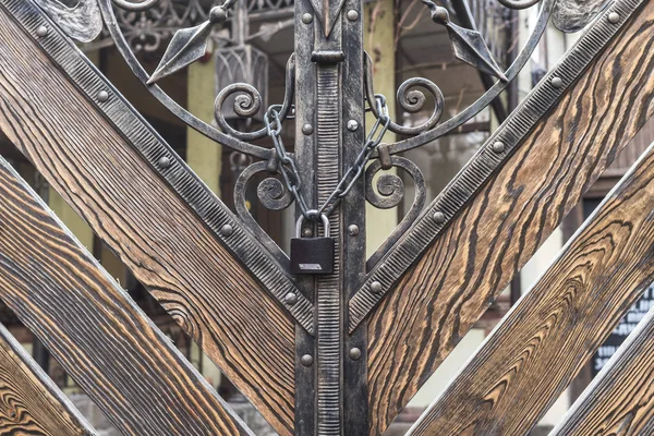 Kapalı giriş. Ahşap Kapı demir kilit. Sahte köy gates. Çit bölge. Zinciri üzerinde kilit. Tarihi bir binada Vintage dış.