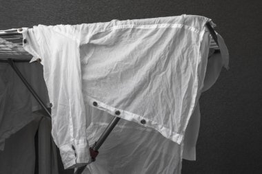 Buruşuk beyaz gömlek. Kurutma makinesi üzerinde yıkanmış kıyafetler. Pamuklu gömlek. Klasik giyim gardırop. Siyah ve beyaz arka plan. Tek renkli görüntüyü. Bir askı forması. Giysi parçası.