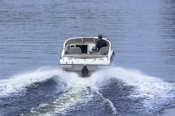 Motor boat in motion. White yacht. Travel by water on a speedboat. Holidays on a cruise on the sea or river. Powerboat rear view. Male hobby. Summer vacation in the open air. Dreams Come True.