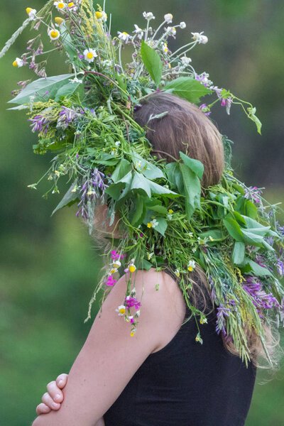Unknown rural girl. Woven from wild flowers wreath. Village traditions and customs. Slavic pagan beliefs. Women's jewelry and amulet. Unity with nature. Happy, calm, peaceful woman.