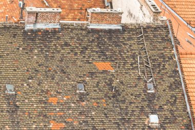 Eski çatıların manzarası. Şehir en üstte. Grunge tarzı dış. Çöken bir ev. Avrupa çatıları. Eski Budapeşte'nin mimarisi. Yüksekten şehir manzarası. Kiremitli çatıda kırık merdivenler.