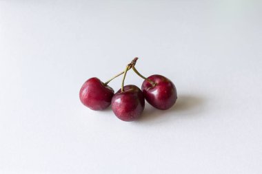 Bir sapta birkaç dut var. İhanet metaforu. Üçüncü tekerlek. İki ya da üç kiraz. Kırmızı meyveli vitaminler. Beyaz arka planda ürünler. Sağlıklı yaz meyveleri ve meyveleri.